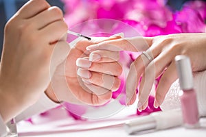 Manicure specialist painting woman gel nail. Art - French manicure