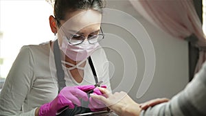 Manicure Specialist Polishing Nails To Client. Nail Beautician Filing Nails To Woman In Nail Salon. Caucasian Woman Is