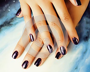 manicure stylish concept: woman fingers with nails purple glitter on nails like cosmos, universe background