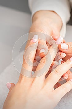 Manicure treatment at beauty spa. A hand of a woman getting a finger massage with oil in a nail salon.