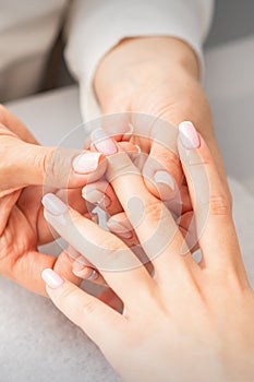 Manicure treatment at beauty spa. A hand of a woman getting a finger massage with oil in a nail salon.