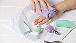 Manicure. The woman wipes her hand with a towel. Manicure tools, nail polishes. Home nail care, SPA, beauty. Long natural nails.