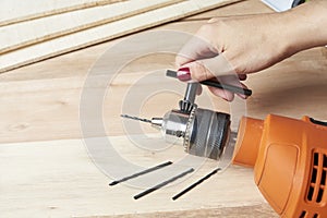 Manicured hand of a young woman changing the drill bit of an electric drill