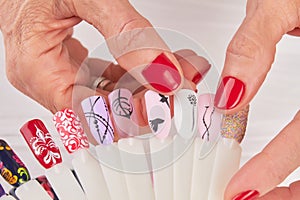 Manicured hands holding nail art samples.