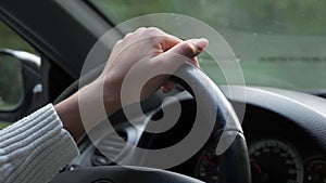 Manicured lady in white pullover hand on steering wheel