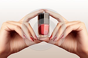 Manicured nails with red nail polish. Manicure with bright nailpolish. Fashion manicure. Shiny gel lacquer in bottle