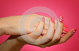 Manicured woman`s nails with pink nailart with flowers.