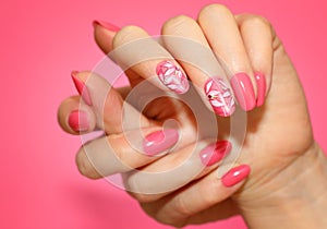 Manicured woman`s nails with pink nailart with flowers. photo