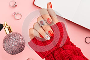 Manicured womans hand in warm wool red sweater. Fashionable valentines day nail design