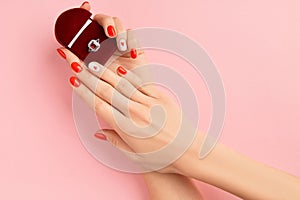 Manicured womans hands holding wedding ring. Fashionable valentines day nail design