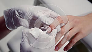 Manicurist applies cover hardener on customer nail with brush in cosmetology salon closeup