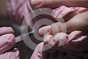 The manicurist applies a layer of gel Polish to the client`s nail. Applying pink nail Polish with a brush.