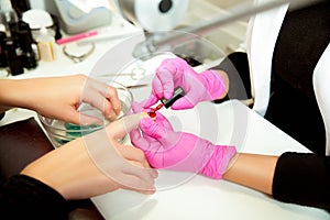 Manicurist applies a lok on nails.