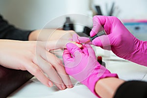 Manicurist applies a lok on nails.