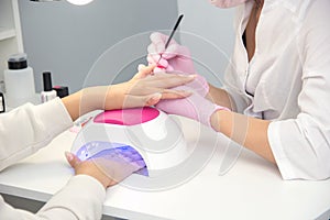 Manicurist apply nail Polish. Close-up of a woman applying nail Polish to her finger nails.Pink nails