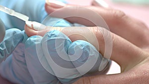 Manicurist applying fixing for nail polish.