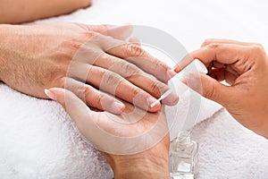 Manicurist Applying Moisturizing Oil On Person`s Hand