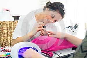 manicurist applying polish to clients right fingernails