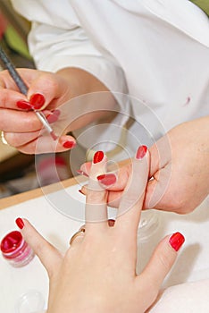 Manicurist applying red nail