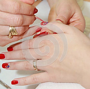 Manicurist applying red nail