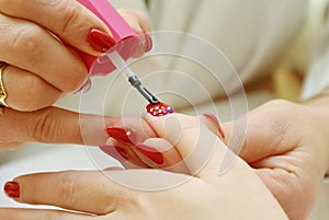 Manicurist applying red nail