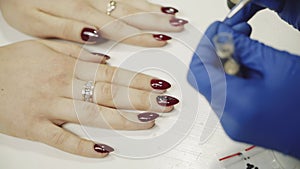 Manicurist applying red nail varnish. Rhinestones on nails