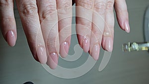 manicurist in black gloves paints nails in beige neutral color close-up beauty salon manicure process with gel polish