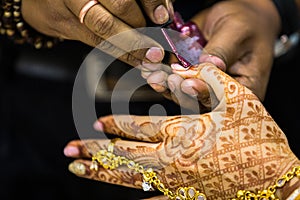 Manicurist doing manicure to indian bride hand lacquer polish, painting fingernails,