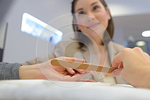 Manicurist doing nail filing at salon