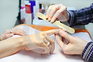 Manicurist hands make manicure by nailfile photo