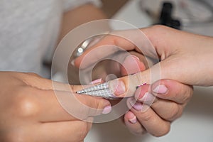 Manicurist makes escalating of nails in beauty salon