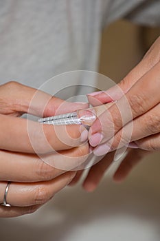 Manicurist makes escalating of nails in beauty salon