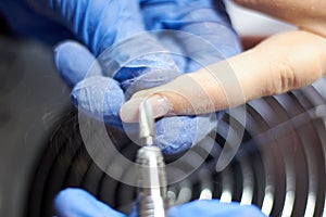 A manicurist makes a girl's nails. Sawing off old nails. Close-up