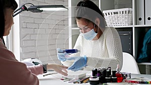 Manicurist making a manicure in the salon. Master servising her client. Nails care procedure.