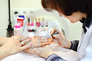Manicurist manicures woman by pink nail polish