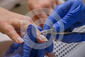 Manicurist master removing cuticles with manicure scissors