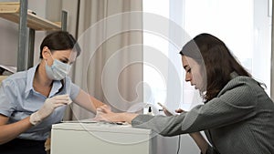 Manicurist master woman is polishing client's nails using file in beauty salon.