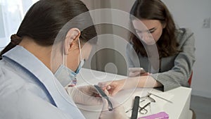 Manicurist master woman is polishing client's nails using file in beauty salon.