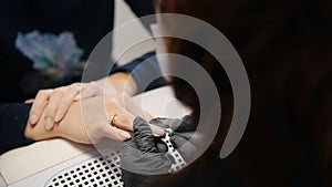 Manicurist in medical mask doing manicure for attractive woman in beauty salon