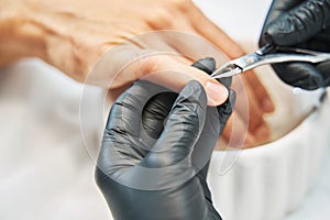 Manicurist nipping away skin from nail with cuticle cutter photo