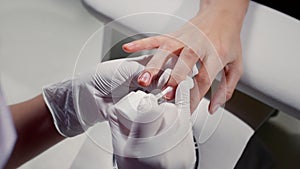 Manicurist paints the client's nails with a colorless transparent varnish. Woman takes care manicure