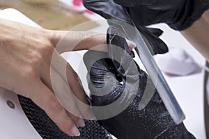 A manicurist polishes a client s nails preparing for coarse gel coating of their hands.