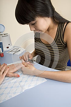 Manicurist polishing client's nails