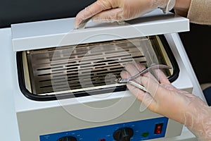Manicurist prepare nail nipper for hot air sterilization in autoclave photo