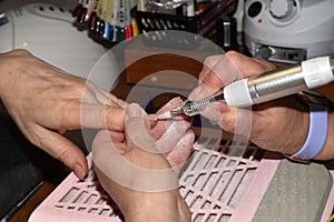 A manicurist processes fingernails with a milling cutter.