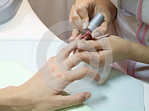 Manicurist putting red nail polish