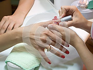 Manicurist putting red nail polish photo