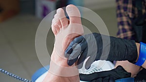 Manicurist removes dry skin from feet of man. She uses electrical hardware machine for russian manicure. Close up view.