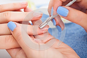 Manicurist removing cuticle from nail