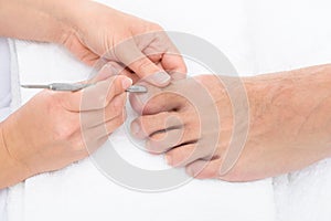 Manicurist removing cuticle from the nail